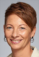 Porträt einer lächelnden Frau mit kurzem, braunem Haar und Ohrhängern.