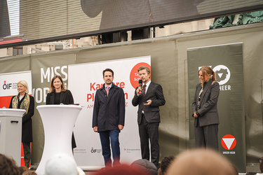 Fünf Personen stehen auf dem Rednerpult